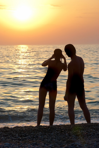 Hombre, mujer y puesta de sol sobre el mar