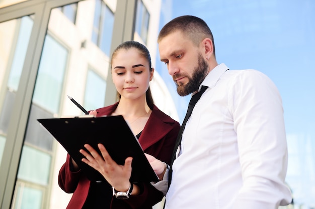 Hombre y mujer en ropa de negocios firman documentos o un contrato