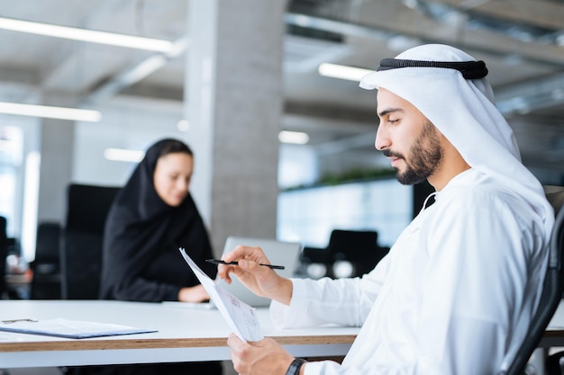 Hombre y mujer con ropa tradicional trabajando en una oficina de negocios de Dubai