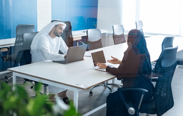 Hombre y mujer con ropa tradicional trabajando en una oficina de negocios de Dubai