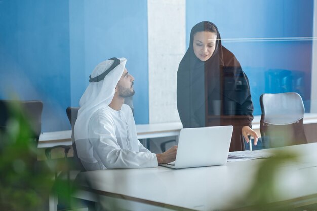 Hombre y mujer con ropa tradicional trabajando en una oficina de negocios de Dubai