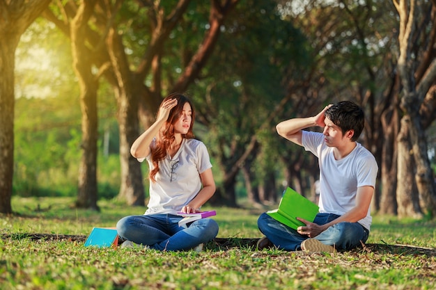 hombre y mujer sentada y leyendo un libro en el parque