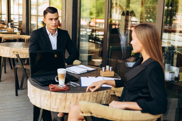 Hombre y mujer sentados en un café durante una reunión de negocios y almuerzo