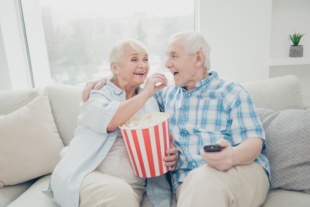 Hombre y mujer sentados en un sofá comiendo palomitas de maíz