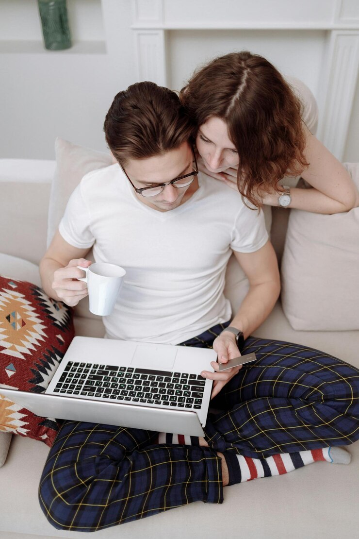 Foto un hombre y una mujer sentados en un sofá con una computadora portátil y una taza de café