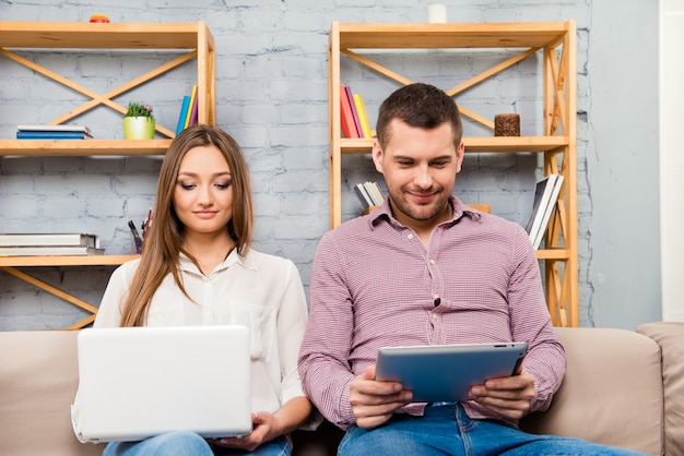 Hombre y mujer, sentar sofá, con, computadora portátil, y, tableta