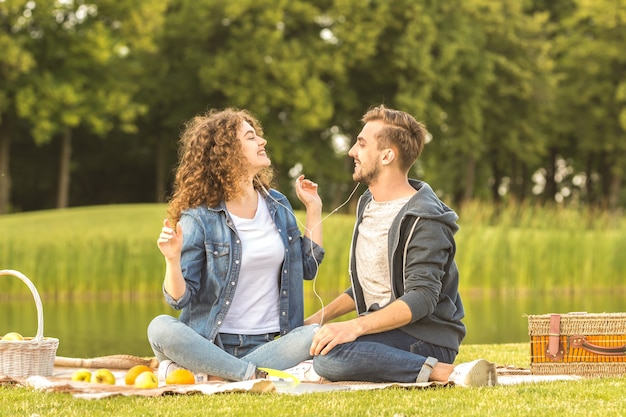 El hombre y la mujer se sientan con auriculares en el parque.