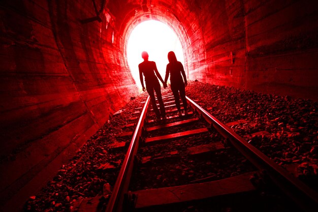 Foto hombre y mujer de silueta de pie en una vía ferroviaria en un túnel