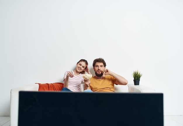 Foto hombre y mujer en sofá con interior de sala de flores y pantalla de tv