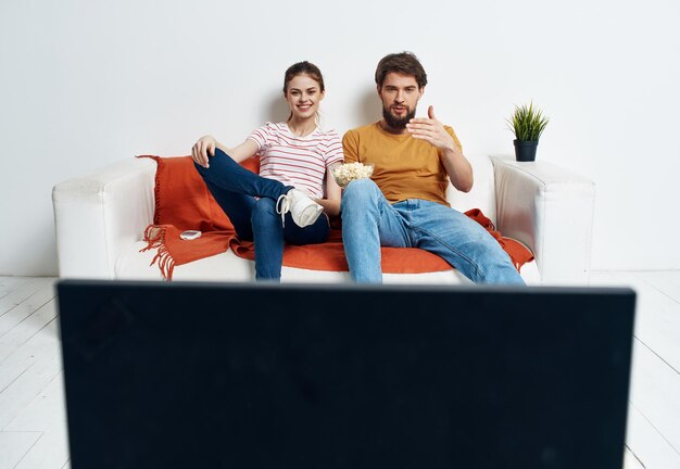 Un hombre y una mujer en el sofá viendo la televisión en el interior viendo el programa