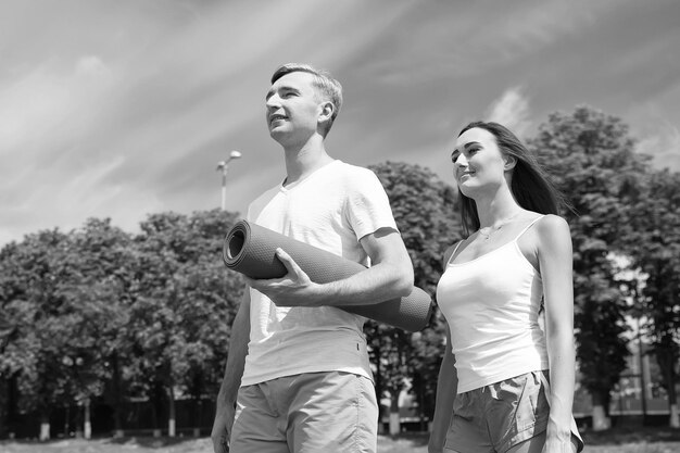 Hombre y mujer soleado al aire libre en el cielo azul Actividad de verano y energía Entrenador y salud Deporte y fitness Pareja enamorada relajarse después del entrenamiento con colchoneta de fitness