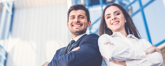 El hombre y la mujer de la sonrisa están parados en el fondo del centro de oficinas