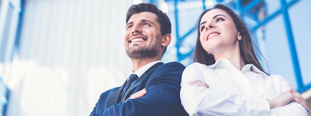 El hombre y la mujer de la sonrisa están parados en el fondo del centro de oficinas