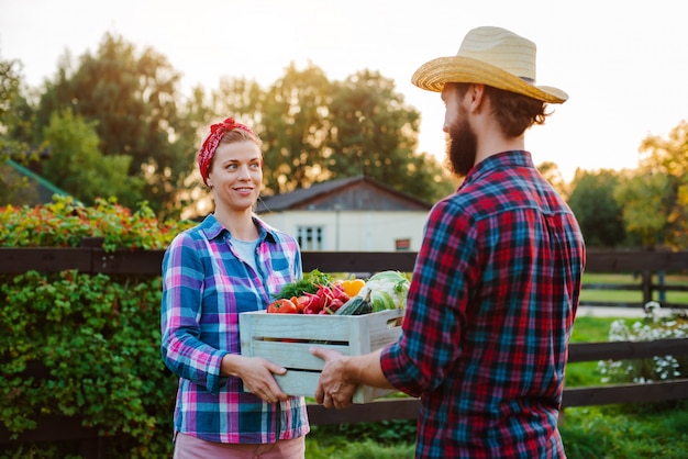 Un hombre y una mujer sosteniendo una caja con un cultivo de hortalizas