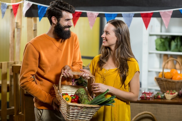 Hombre y mujer sosteniendo una canasta de verduras en la tienda de comestibles