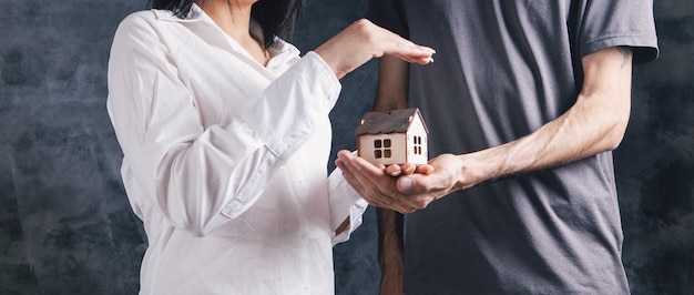 Un hombre y una mujer sosteniendo una casa.