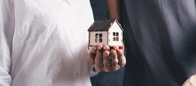 Un hombre y una mujer sosteniendo una casa.