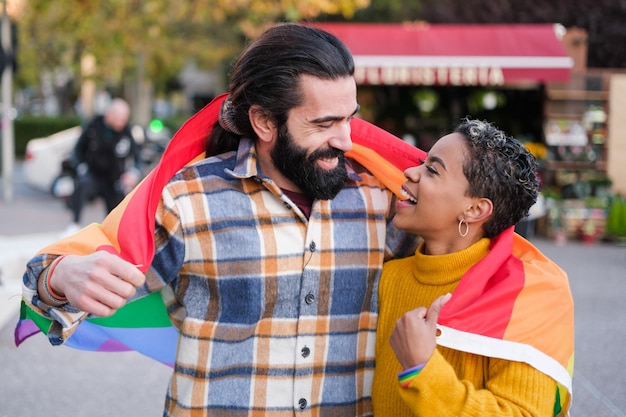 Un hombre y una mujer sostienen una bandera del arco iris.