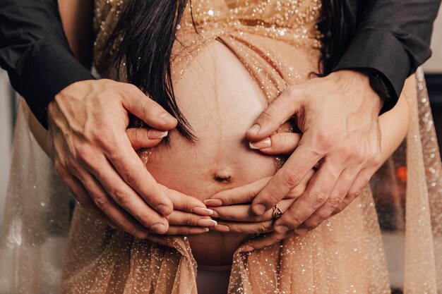 El hombre y la mujer sostienen el vientre redondo con un niño dentro. Pareja embarazada esperando bebé