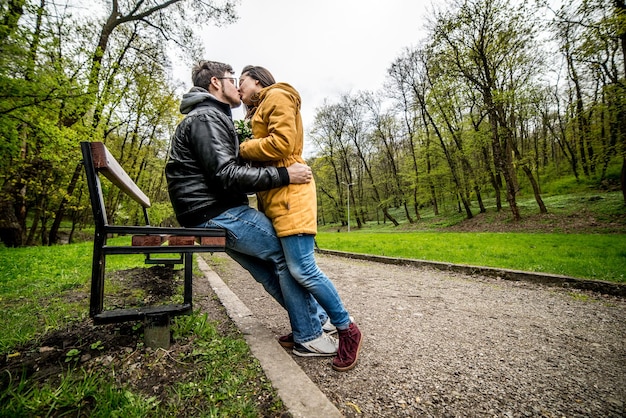 Hombre y mujer tienen una cita en un banco en el parque de primavera