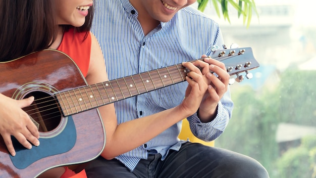 hombre y mujer tocando la guitarra juntos