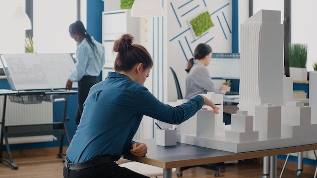Hombre y mujer trabajando juntos con planos y modelo de construcción para proyecto urbano. Compañeros de trabajo que diseñan el diseño y la estructura de la construcción para crear un desarrollo arquitectónico.