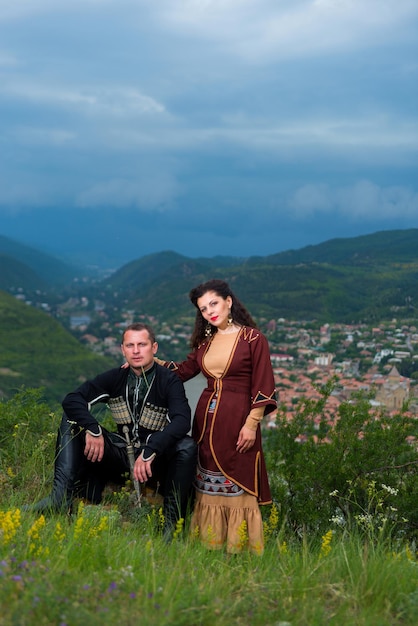 Foto hombre y mujer en traje nacional georgiano sobre un fondo de montañas