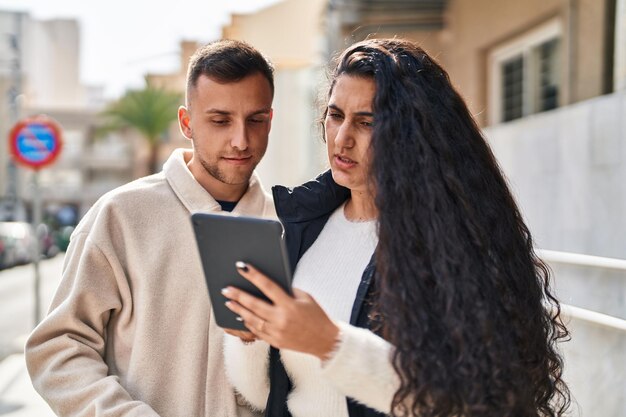 Hombre y mujer usando touchpad en la calle