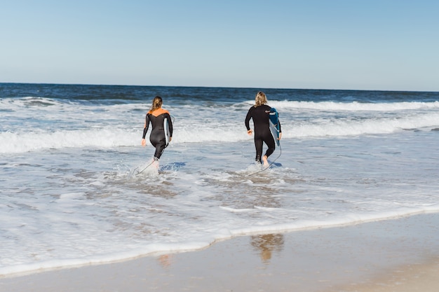 hombre y mujer van al océano con tablas de surf. hombre y niña van a surfear