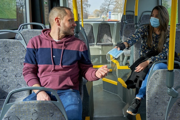 Hombre y mujer viajan al autobús con una máscara