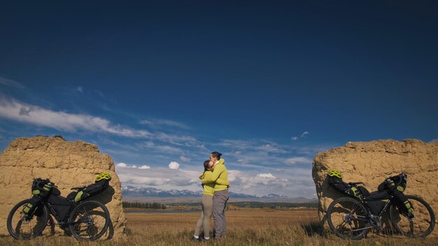 El hombre y la mujer viajan en cicloturismo de terreno mixto con bikepacking. Las dos personas viajan con bolsas de bicicletas. Montaña nevada, arco de piedra.