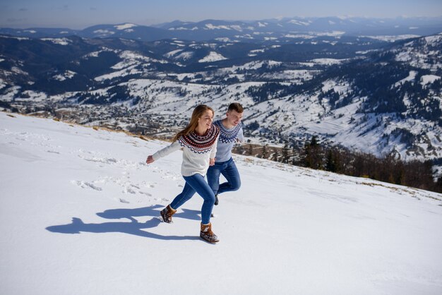 Hombre y mujer vistiendo ropa tejida jugando en la montaña nevada.