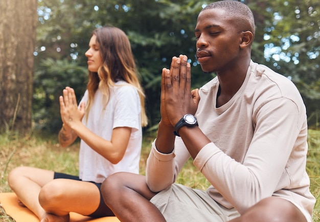 Hombre y mujer de yoga en la mano de oración posan juntos en el césped natural y al aire libre Meditación zen y amigos atléticos haciendo pilates al aire libre en el suelo o en el campo para la salud, el bienestar y el bienestar