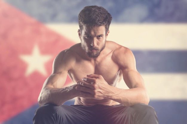 Hombre musculoso con bandera cubana detrás