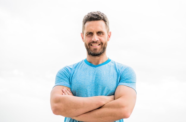 Hombre musculoso con barba hombre feliz aislado en blanco deportista con entrenador de cuerpo atlético en gimnasio después de entrenamiento hombre atleta en azul deporte camiseta ropa deportiva moda feliz sonriente hombre