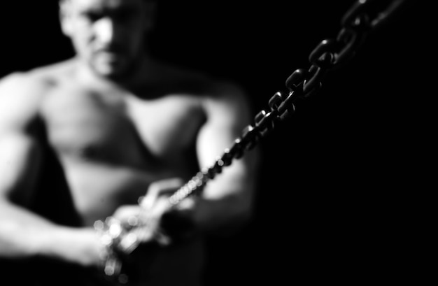 Hombre musculoso con cadena de hierro cadena de enfoque selectivo fuerte concepto de resistencia