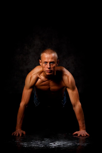 Foto hombre musculoso calentando y haciendo algunas flexiones en el gimnasio