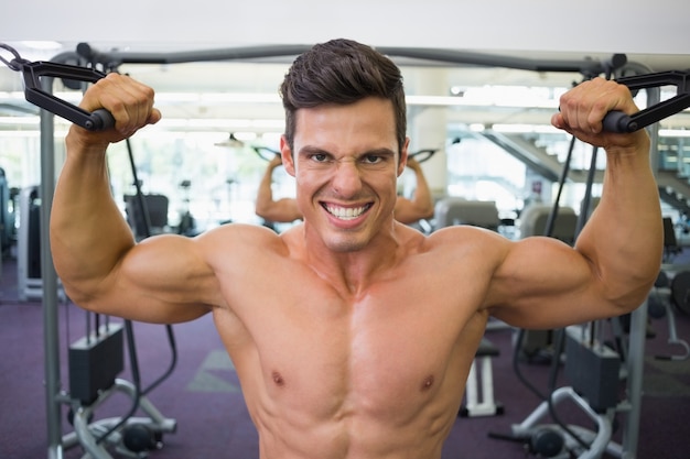 Hombre musculoso sin camisa con banda de resistencia en el gimnasio