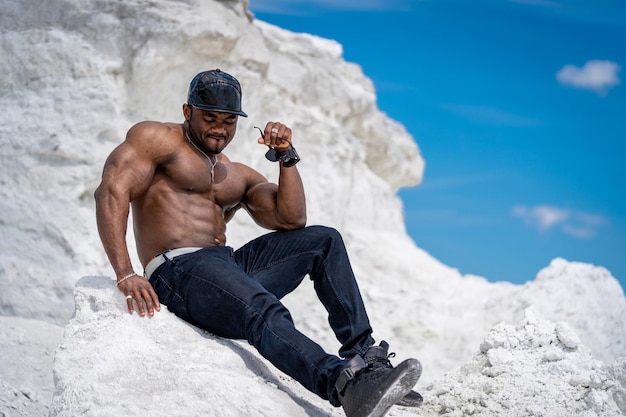 Hombre musculoso sin camisa sentado y bronceado en el sol de verano Hombre deportivo al aire libre con torso musculoso desnudo