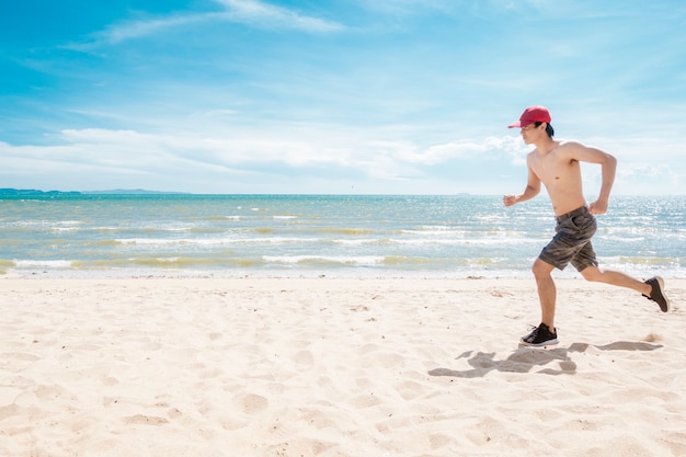 Hombre musculoso corre en la playa