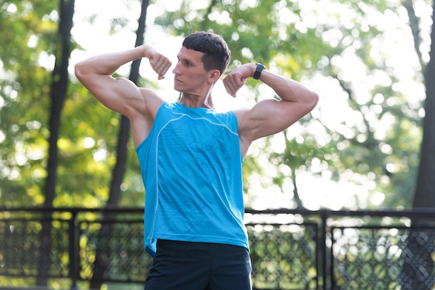 Hombre musculoso culturista mostrando bíceps y tríceps