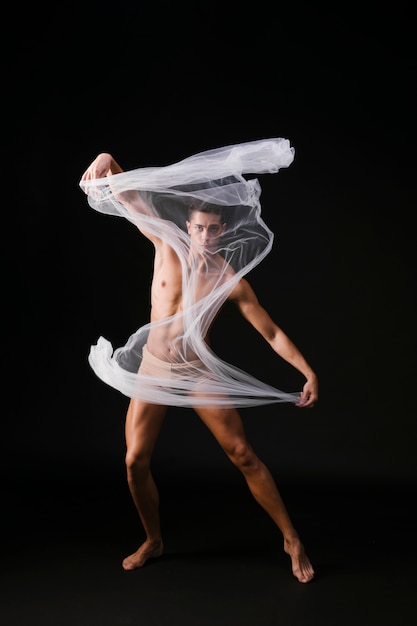 Foto hombre musculoso desnudo de pie con un paño blanco y mirando a la cámara