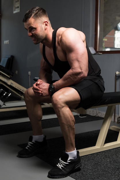 Hombre musculoso después del ejercicio descansando en el gimnasio