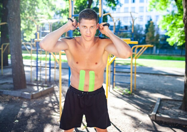 Hombre musculoso entrenamiento con cuerda de fitness en el campo de deportes