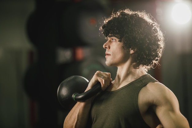 Un hombre musculoso está entrenando duro con pesas rusas en el gimnasio.