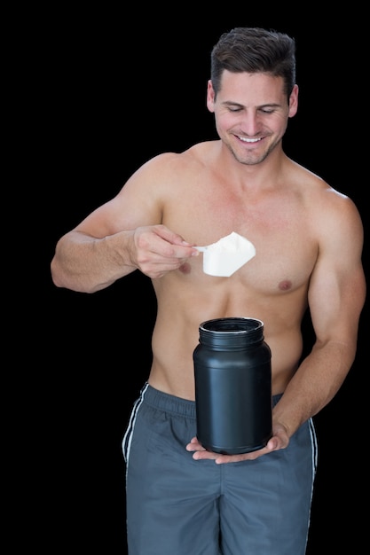 Hombre musculoso feliz recogiendo polvo de proteína