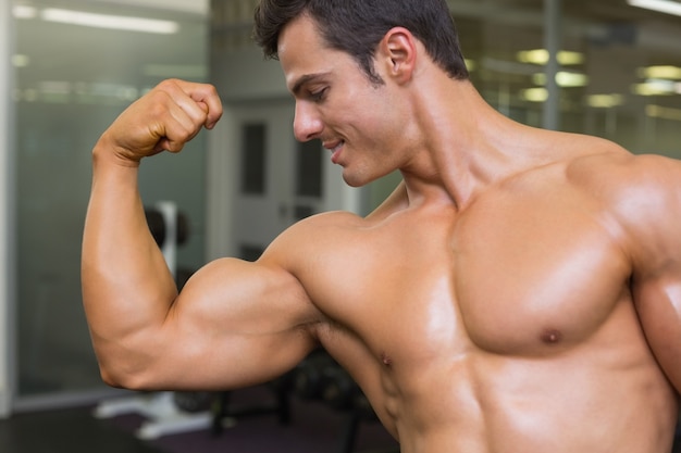 Hombre musculoso flexionando los músculos en el gimnasio