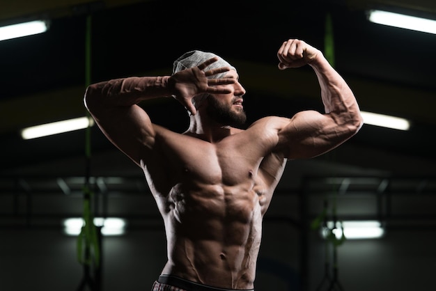 Hombre musculoso flexionando los músculos en el gimnasio