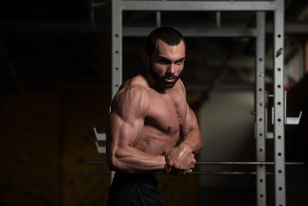 Hombre musculoso flexionando los músculos en el gimnasio