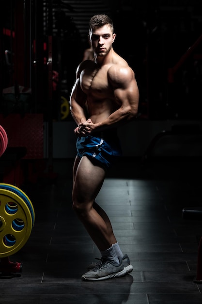 Hombre musculoso flexionando los músculos en el gimnasio